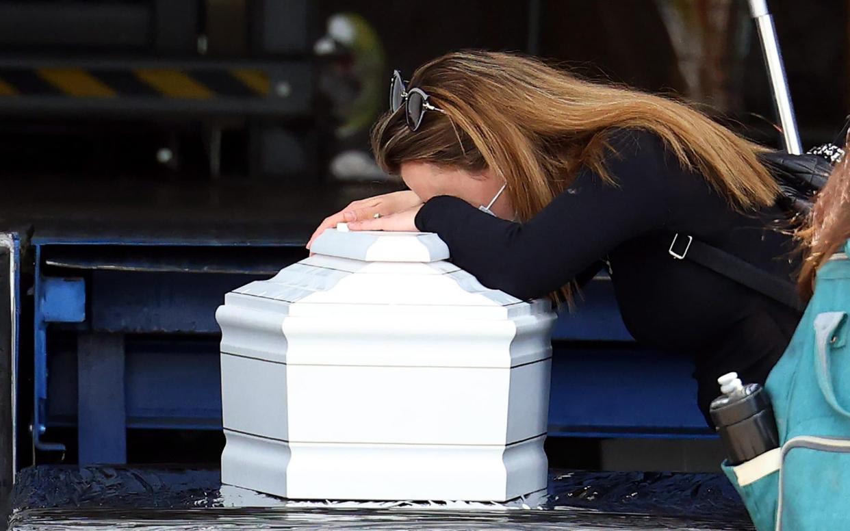 A woman weeps over a small white coffin during a ceremony for the five members of an Israeli family who died in the cable car accident - Shutterstock