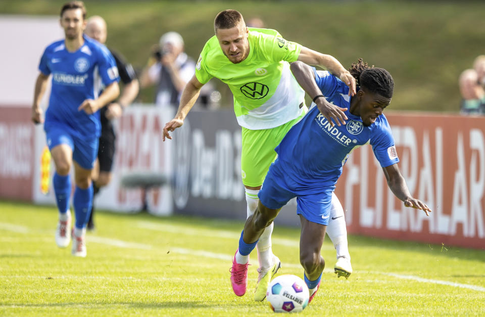 Wolfsburg's Mattias Svanberg, left, fights for the ball against TUS Makkabi's Brian Petnga during the German Soccer Cup match between TuS Makkabi and VfL Wolfsburg at Mommsenstadion stadium, Berlin, Sunday Aug. 13, 2023. (Andreas Gora/dpa via AP)