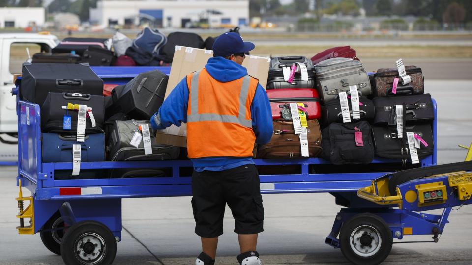 A ground operations employee loads baggage onto a Southwest Airlines Co. Boeing Co. 737 aircraft on the tarmac at John Wayne Airport (SNA) in Santa Ana, California