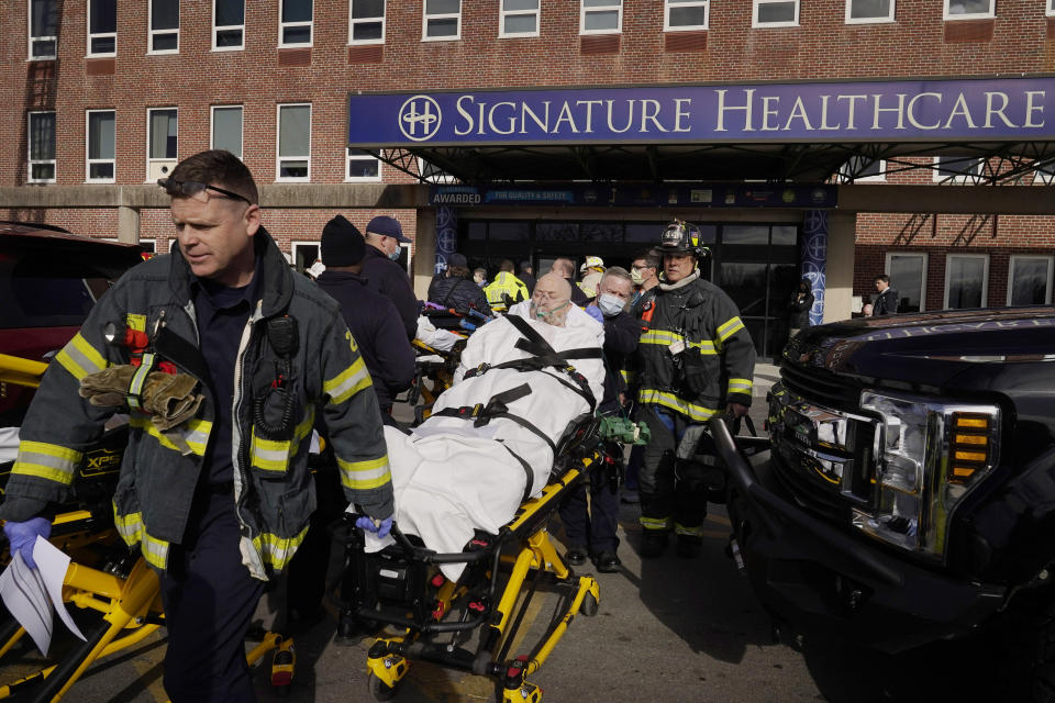 A patient, center, is evacuated from Signature Healthcare Brockton Hospital, Tuesday, Feb. 7, 2023, in Brockton, Mass. A fire at the hospital's electrical transformer forced an undetermined number of evacuations Tuesday morning and power was shut off to the building for safety reasons, officials said. (AP Photo/Steven Senne)