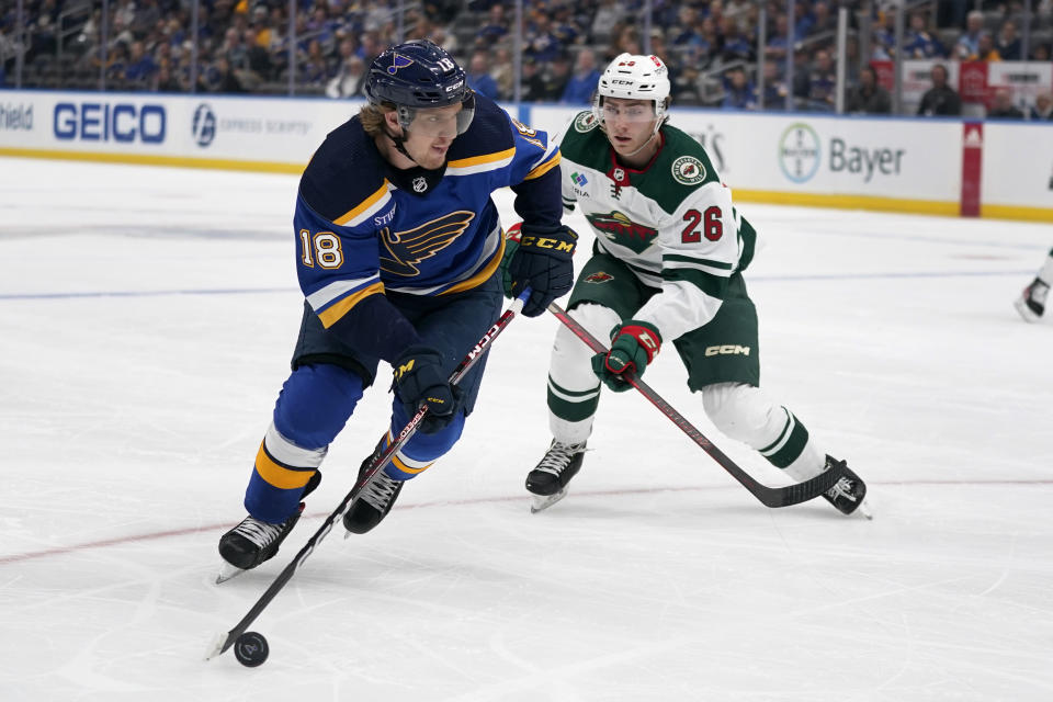 St. Louis Blues' Robert Thomas (18) handles the puck as Minnesota Wild's Connor Dewar (26) defends during the first period of a preseason NHL hockey game Tuesday, Oct. 4, 2022, in St. Louis. (AP Photo/Jeff Roberson)