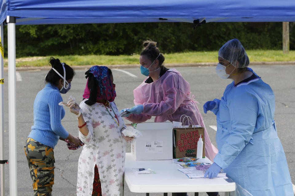 Richmond City Health District workers check in residents for COVID-19 testing at a site set up by the Virginia National Guard Tuesday May 5, 2020, in Richmond, Va. (AP Photo/Steve Helber)
