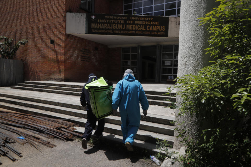 Pharmacist Bikram Bhadel, right, and his friend Indra Newar, a taxi driver, deliver food at Teaching Hospital in Kathmandu, Nepal, Monday, Aug. 31, 2020. At one of the largest hospitals in Nepal, a pharmacist and taxi driver have teamed up to feed COVID-19 patients, doctors, nurses and health workers. Due to lockdowns, the cafeteria and nearby cafes have closed, leaving more than 200 staffers, patients and their families without food. The two friends have taken their own money and donations and put it to use buying groceries, renting a kitchen and paying helpers to provide the meals. (AP Photo/Niranjan Shrestha)