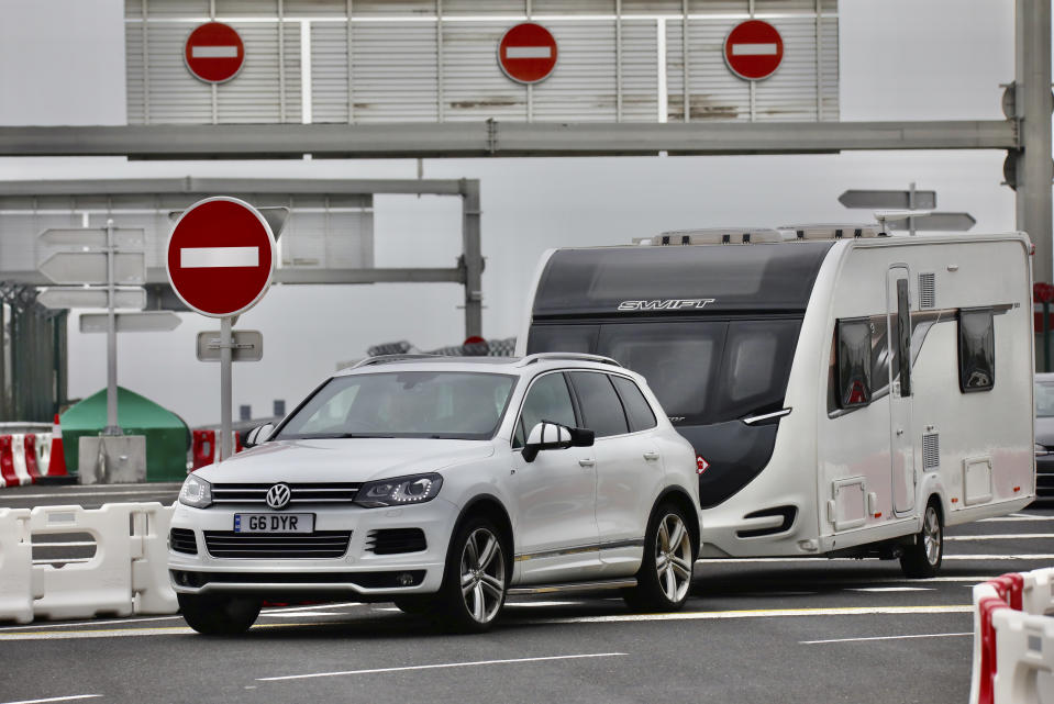 People queue in line to check-in for the Euro Tunnel train to the U.K. in Coquelles, France, Friday Aug.14, 2020. British holiday makers in France were mulling whether to return home early Friday to avoid having to self-isolate for 14 days following the U.K. government's decision to reimpose quarantine restrictions on France amid a recent pick-up in coronavirus infections. (AP Photo/Olivier Matthys)