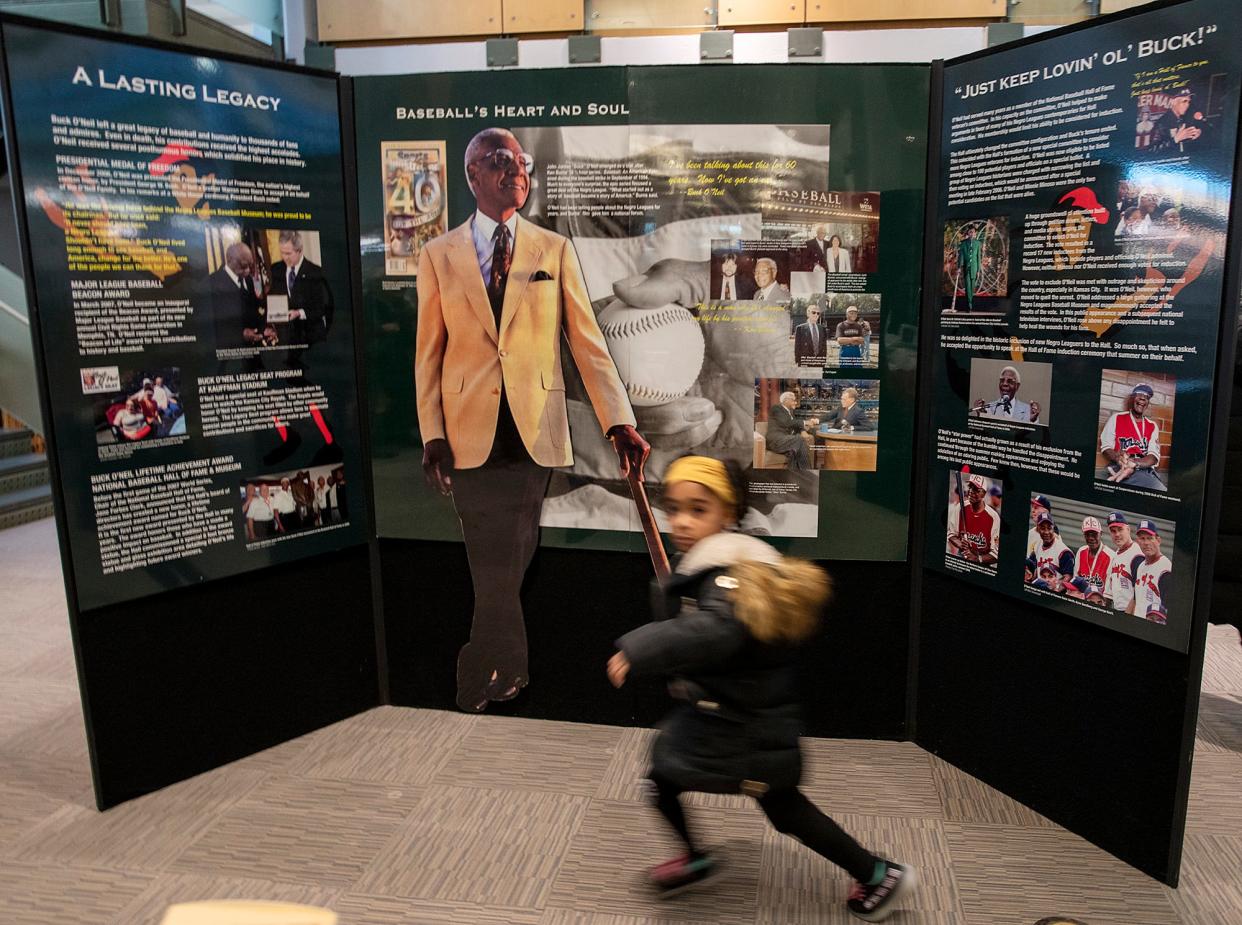 A child runs past a display panel on loan from the Negro Leagues Baseball Museum at the Worcester Public Library Wednesday. The display highlights the life of baseball player, scout and coach Buck O’Neil.