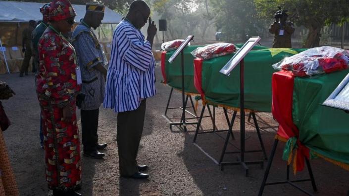 A relative of the former leader and revolutionary Thomas Sankara’s companion pays respects while standing by flag-draped coffins of Sankara and his companions before the burial of their remains in Ouagadougou, Burkina Faso February 23, 2023