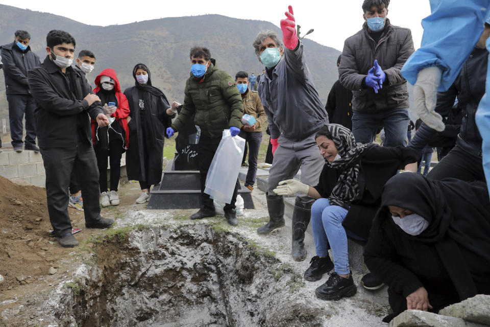 Relatives of Keyumars Ziaee, 60, who died from COVID-19 mourn over his grave at a cemetery in the Shir Kola village on the outskirts of the city of Ghaemshahr, in northern Iran, Wednesday, Dec. 16, 2020. (AP Photo/Ebrahim Noroozi)