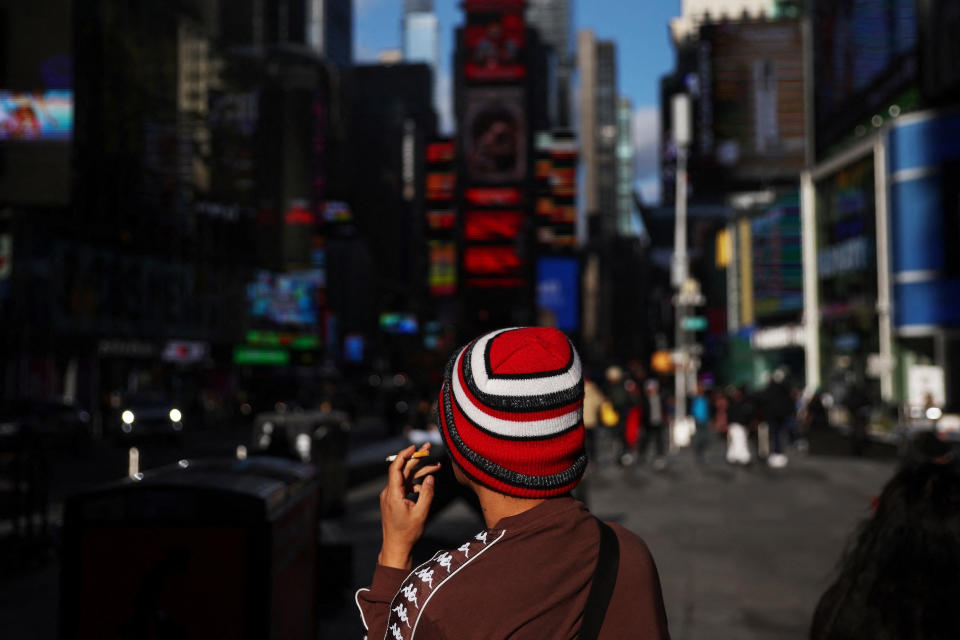 A man smokes a cigarette while sitting in the Times Square section of New York City, U.S., January 18, 2023.  REUTERS/Shannon Stapleton