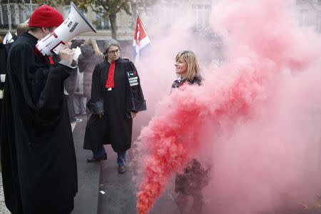 Smoke from an emergency flare fills the air as French lawyers, notaries and bailiffs attend a national protest against a government reform plan to deregulate their profession in Paris December 10, 2014. REUTERS/Charles Platiau