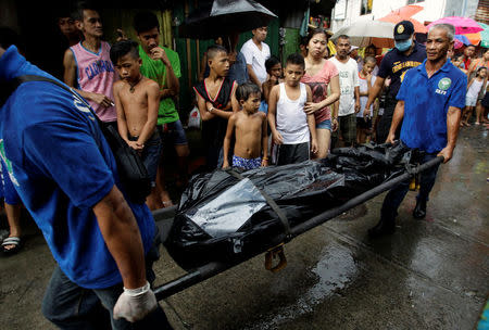 Funeral workers carry a cadaver bag containing the body of a man, past bystanders, who police said was killed during a drug buy bust operation in Manila in the Philippines, October 12, 2016. REUTERS/Czar Dancel