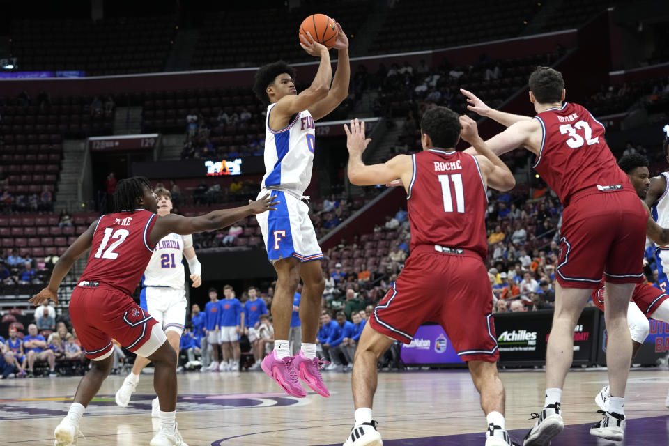 Florida guard Zyon Pullin (0) goes up to shoot as Richmond guard Mikkel Tyne (12), Jason Roche (11) and Neal Quinn (32) defend during the first half of the NCAA college Orange Bowl Classic basketball game, Saturday, Dec. 9, 2023, in Sunrise, Fla. (AP Photo/Lynne Sladky)