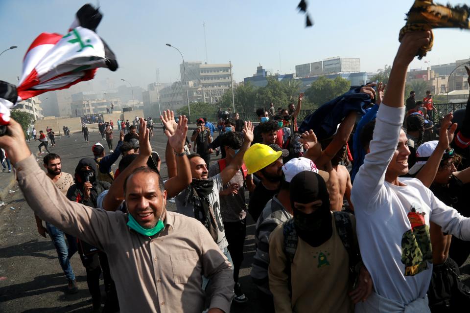 Protesters celebrate while taking control of some concrete walls and barriers set by security forces to close Sinak bridge leading to the Green Zone government areas during clashes between Iraqi security forces and anti-government demonstrators in Baghdad, Iraq, Saturday, Nov. 16, 2019. Iraqi security and medical officials say protesters have pushed closer to the Green Zone, Baghdad's fortified seat of government, after security forces pulled back following a night of violent altercations.(AP Photo/Khalid Mohammed)