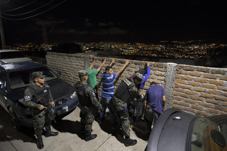 Soldiers check men's ID's as part of a routine patrol in Tegucigalpa, Honduras, Wednesday, Aug. 21, 2019. Ironically, the extradition of drug capos to the U.S. under President Juan Orlando Hernández could have helped build the case against his own brother, in which he is now implicated. (AP Photo/Eduardo Verdugo)