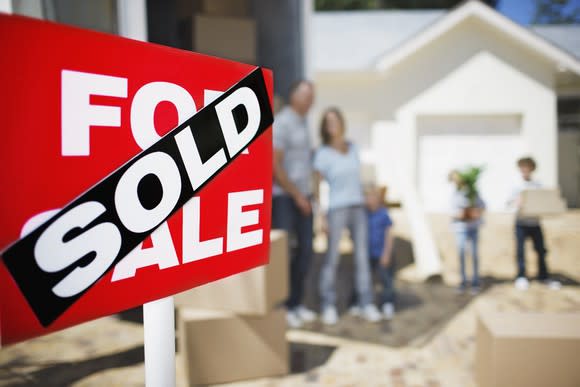 A family standing behind a for sale sign with a sold sign on it