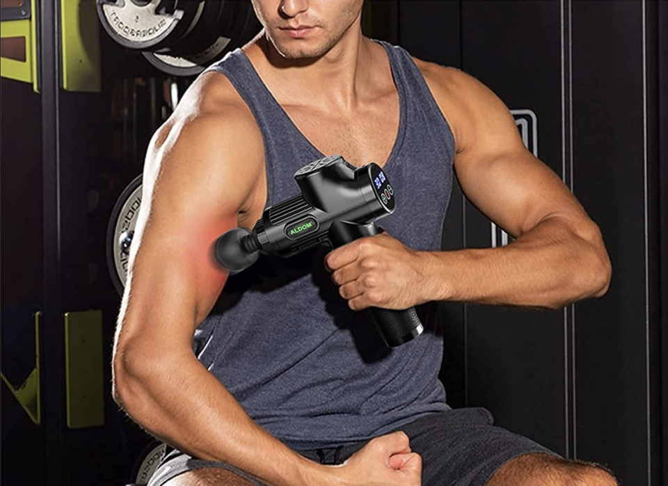 man using Aldom Deep Tissue Massage Gun on arm muscles (Photo via Amazon)