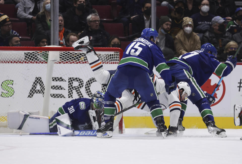 Vancouver Canucks' Matthew Highmore (15) checks Edmonton Oilers' Connor McDavid in front of Vancouver goalie Spencer Martin during overtime in an NHL hockey game, Tuesday, Jan. 25, 2022 in Vancouver, British Columbia. (Darryl Dyck/The Canadian Press via AP)