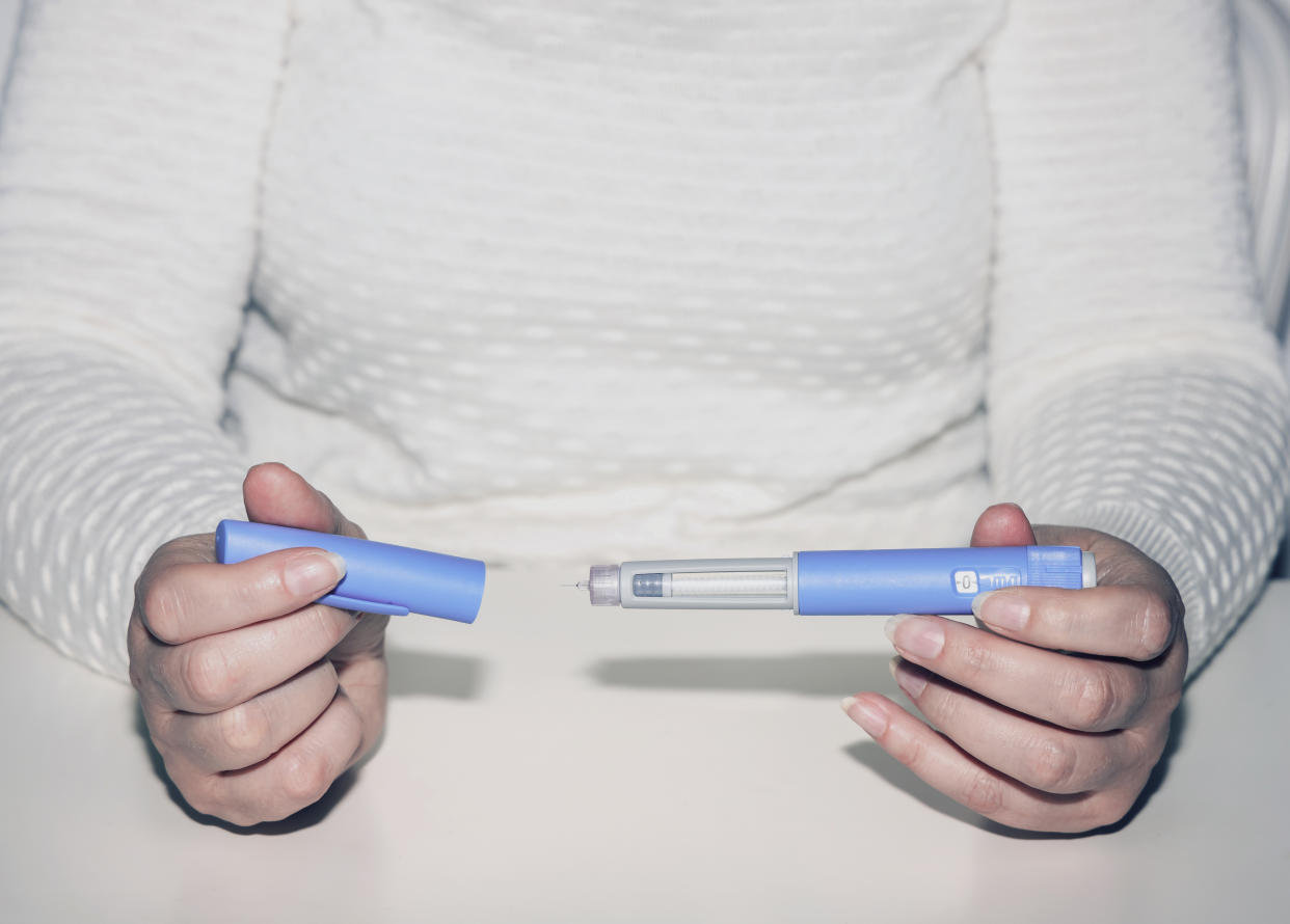 A woman holds a weight-loss drug injection pen