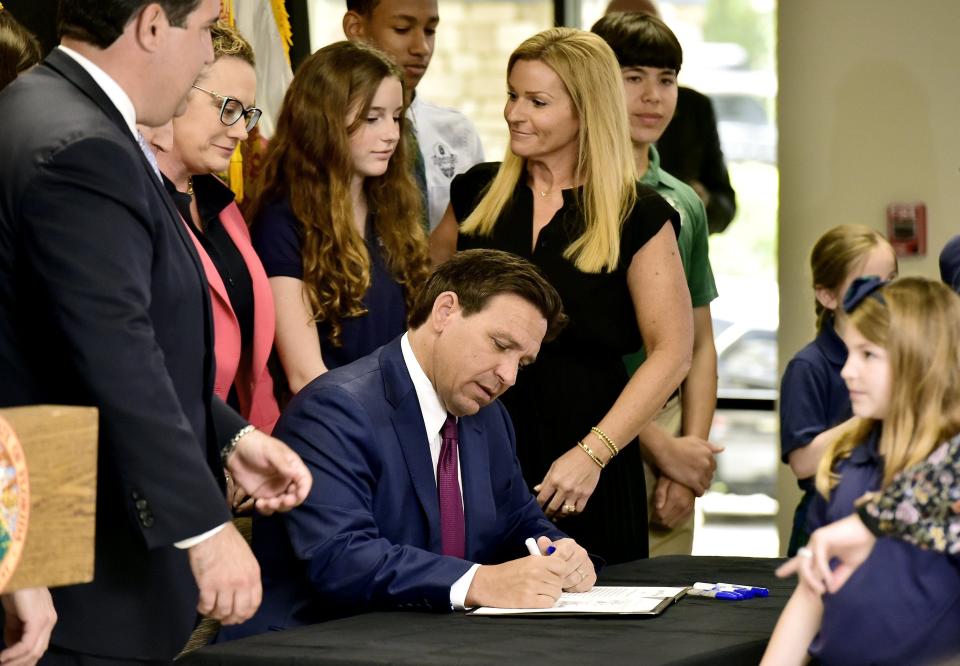 Florida Gov. Ron DeSantis signs the paperwork for Florida House Bill 3 at the Cornerstone Classical Academy in Jacksonville on Monday, March 25, 2024, along with local and state leaders. The bill bans Floridians younger than 16 from "addictive" social media platforms but with exceptions for those who are 14 or 15 and get parental permission.
