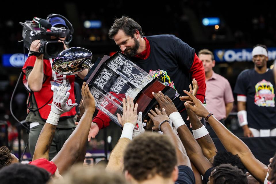 Dec 18, 2021; New Orleans, LA, USA;  Louisiana-Lafayette Ragin Cajuns head coach Michael Desormeaux hands the trophy off to the players against Marshall Thundering Herd after the game at the 2021 New Orleans Bowl at Caesars Superdome. Mandatory Credit: Stephen Lew-USA TODAY Sports