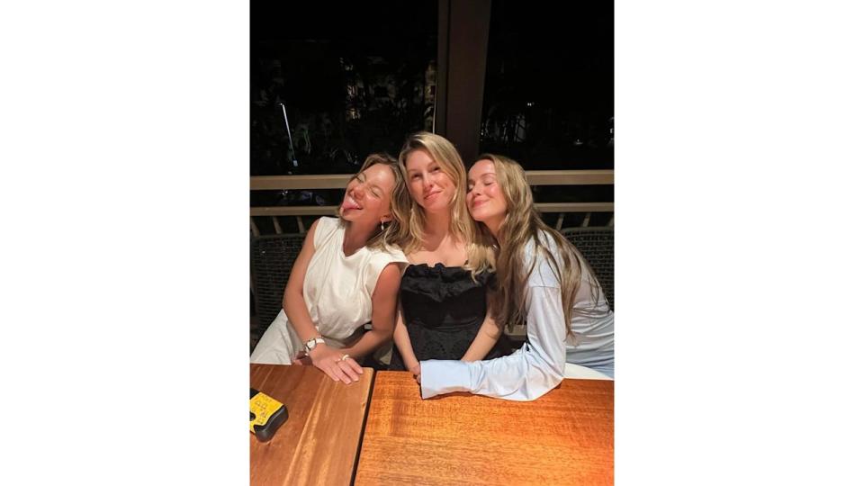 Sydney Sweeney smiling, sat at a table with her friends 