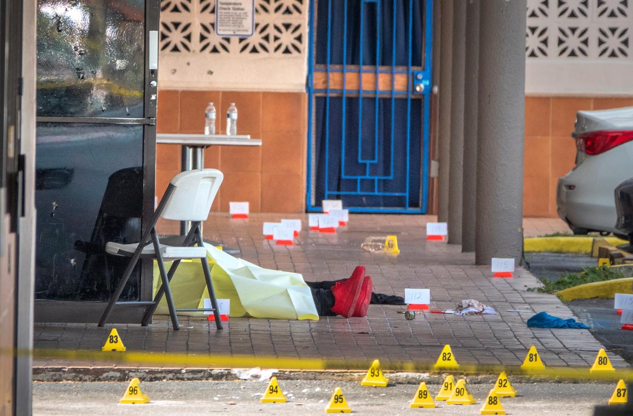 <p>A victim's body is seen at the shooting scene at entrance of the Billiards banquet hall in Miami Gardens</p> (EPA)