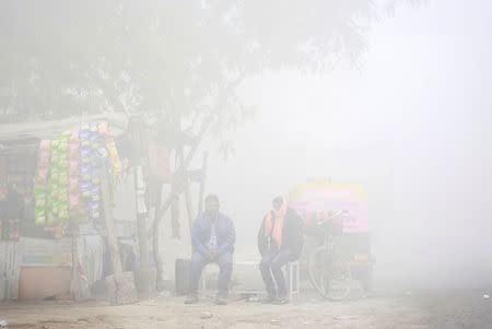 REFILE - QUALITY REPEAT Men sit on a bench beside a makeshift shop during heavy fog in Delhi, India December 1, 2016. REUTERS/Cathal McNaughton