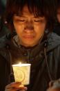 A woman offers prayer with candlelights for the missing passengers of a sunken ferry at Danwon High School in Ansan, South Korea, Thursday, April 17, 2014. An immediate evacuation order was not issued for the ferry that sank off South Korea's southern coast, likely with scores of people trapped inside, because officers on the bridge were trying to stabilize the vessel after it started to list amid confusion and chaos, a crew member said Thursday. (AP Photo/Wonghae Cho)