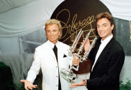 Illusionists Siegfried and Roy react after receiving the second annual Liberace Legend Award at a gala benefit at the famed Liberace mansion in Las Vegas, May 17, 1995. The two were honored for their tenure in the world of entertainment, their devotion to wildlife conservation and significant contributions to the community. (AP Photo/Lennox McLendon)