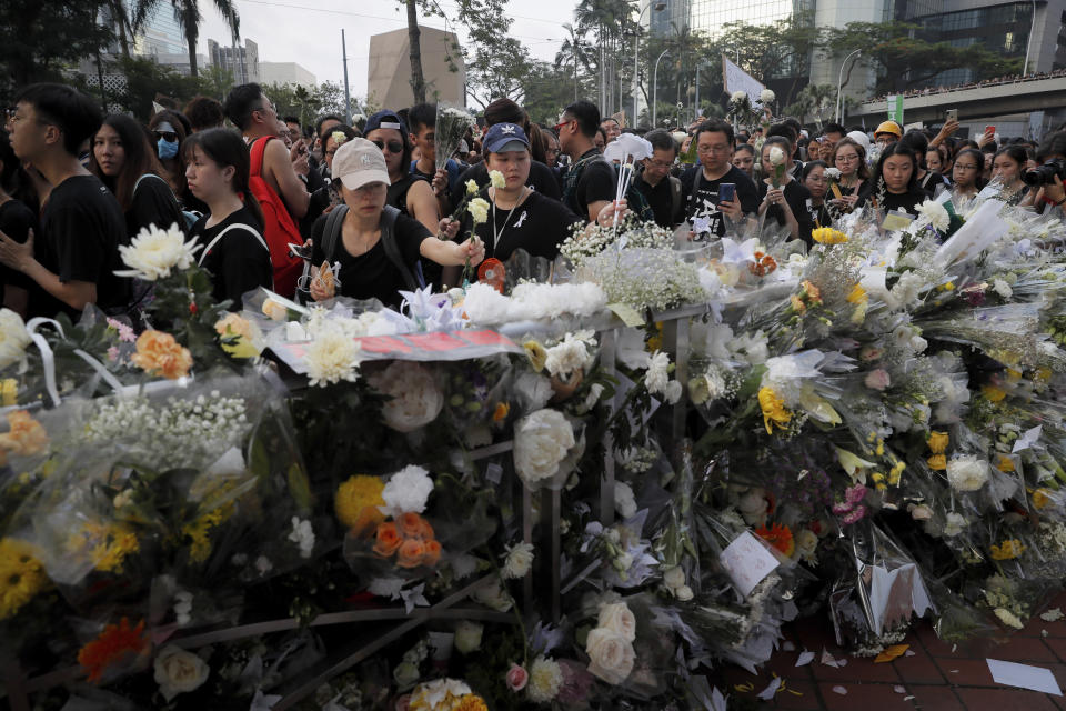 Mourners stop by a makeshift memorial, to lay flowers and pray for a man who fell to his death on Saturday after hanging a protest banner against an extradition bill in Hong Kong Sunday, June 16, 2019. Hong Kong residents were gathering Sunday for another mass protest over an unpopular extradition bill that has highlighted the territory's apprehension about relations with mainland China. (AP Photo/Kin Cheung)