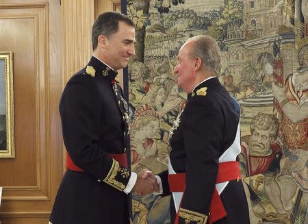 Spain's King Juan Carlos (R) shakes hands with new King Felipe VI, wearing the Sash of Captain-General, as they attend a ceremony at La Zarzuela Palace in Madrid, June 19, 2014. REUTERS/Zipi/Pool