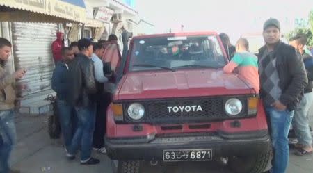 People gather around a vehicle at a site after an attack by Islamist fighters on an army and police barracks in the town of Ben Guerdan, Tunisia, near the Libyan border, in this March 7, 2016 still image taken from video. REUTERS/Reuters TV