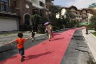 A family walks in front for are houses for sale at the replica village of Austria's UNESCO heritage site, Hallstatt, in China's southern city of Huizhou in Guangdong province, June 1, 2012.