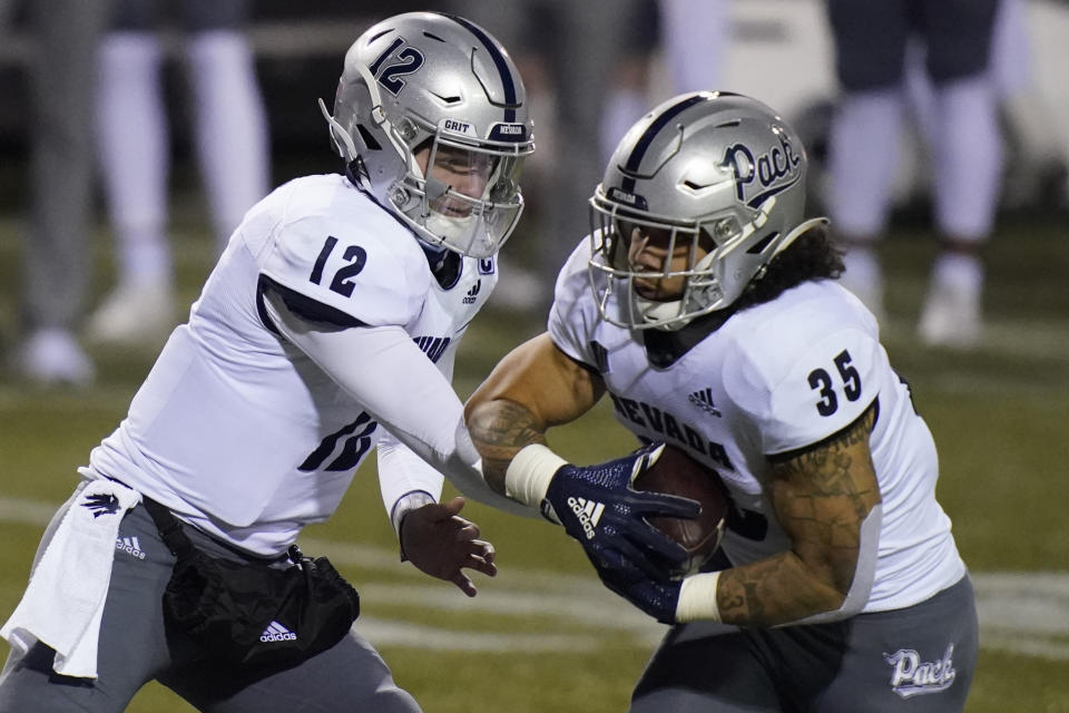 Nevada quarterback Carson Strong (12) hands off the ball to running back Toa Taua (35) during the first half of the team's NCAA college football game against San Jose State, Friday, Dec. 11, 2020, in Las Vegas. (AP Photo/John Locher)