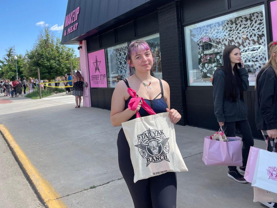 Woman holding Jeffree Star cosmetics bag in front of black building