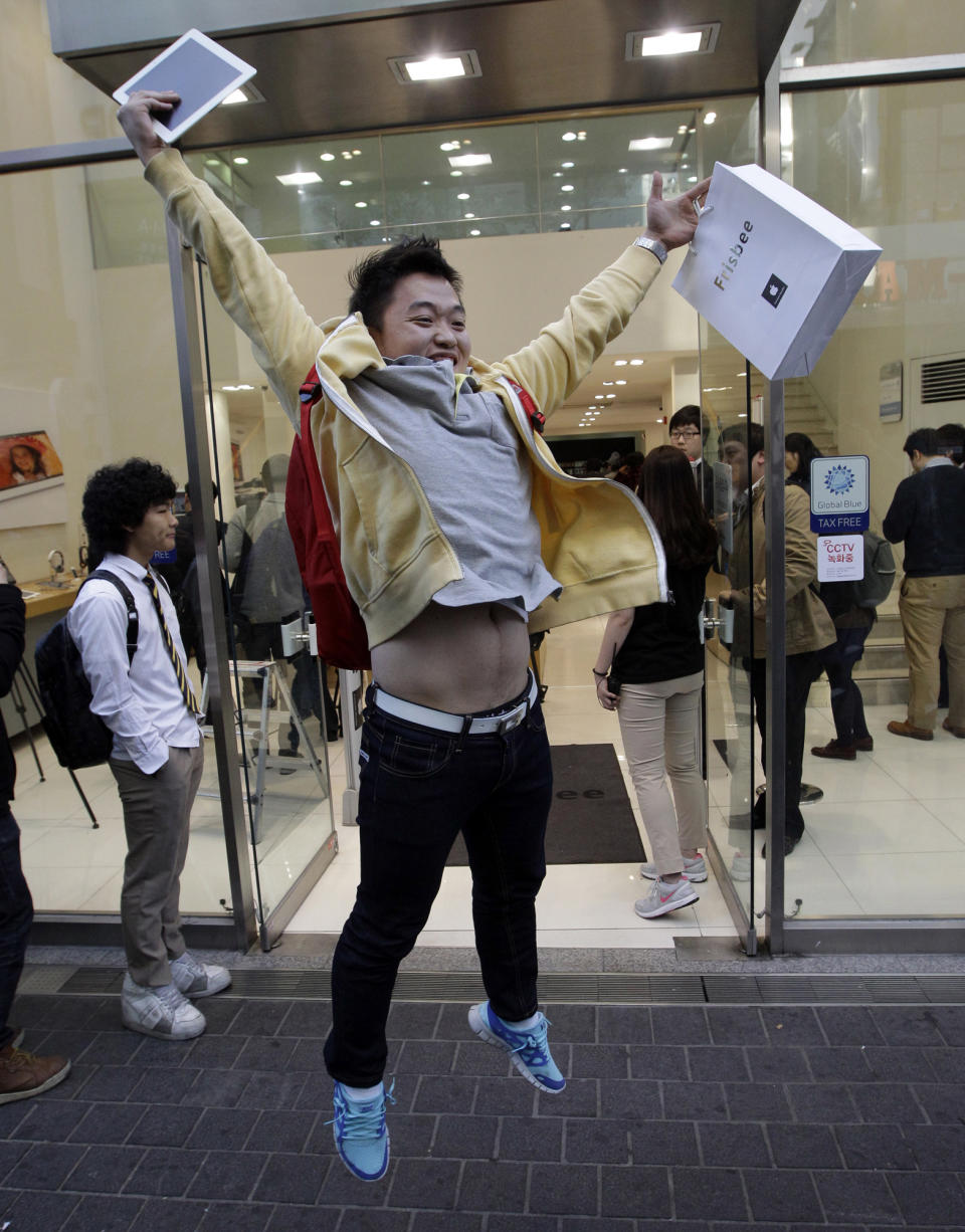 FILE- In this Friday, April 20, 2012, file photo, Baek Sung-min, 23, jumps in joy after purchasing a new iPad tablet computer at an Apple store in Seoul, South Korea. Apple is set to report another record quarterly profit on Tuesday, April 24, 2012, continuing the relentless string of results that’s made it the world’s most valuable company. (AP Photo/Lee Jin-man)