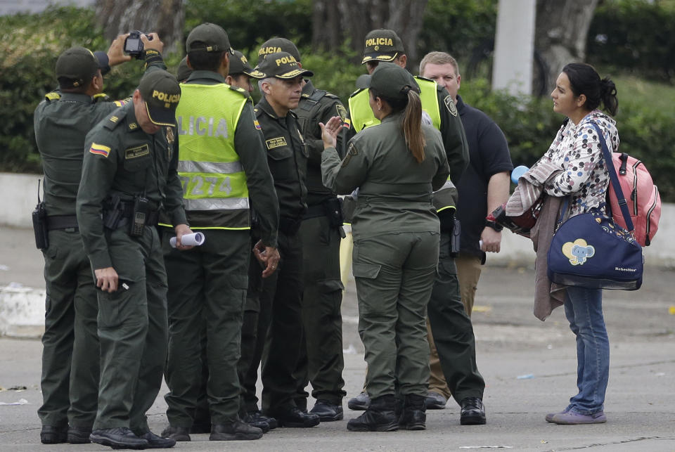 A Venezuelan National Guard soldier, back to camera with ponytail, defects her post near the Simon Bolivar International Bridge in La Parada, near Cucuta, Colombia, on the border with Venezuela, early Sunday, Feb. 24, 2019. Colombian police said that the baby she's holding, covered, and the woman at right are her children. A U.S.-backed drive to deliver foreign aid to Venezuela on Saturday met strong resistance as troops loyal to President Nicolas Maduro blocked the convoys at the border and fired tear gas on protesters. (AP Photo/Fernando Vergara)