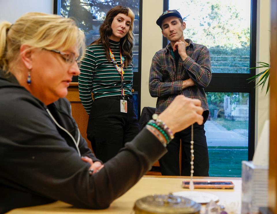 Wendy Smith, 50, of Redford, left, a member of the Motor City Ghost Hunters, uses a pendulum to communicate with a spirit at the Redford Public Library as Jessica Doster, 28, and Krystian Quint, 26, both of Hamtramck, watch on Saturday, Oct. 8, 2022. The library invited the group to come in after hours to use their equipment to look for spirits while also allowing over 20 library visitors who had signed up earlier to go along on the search.