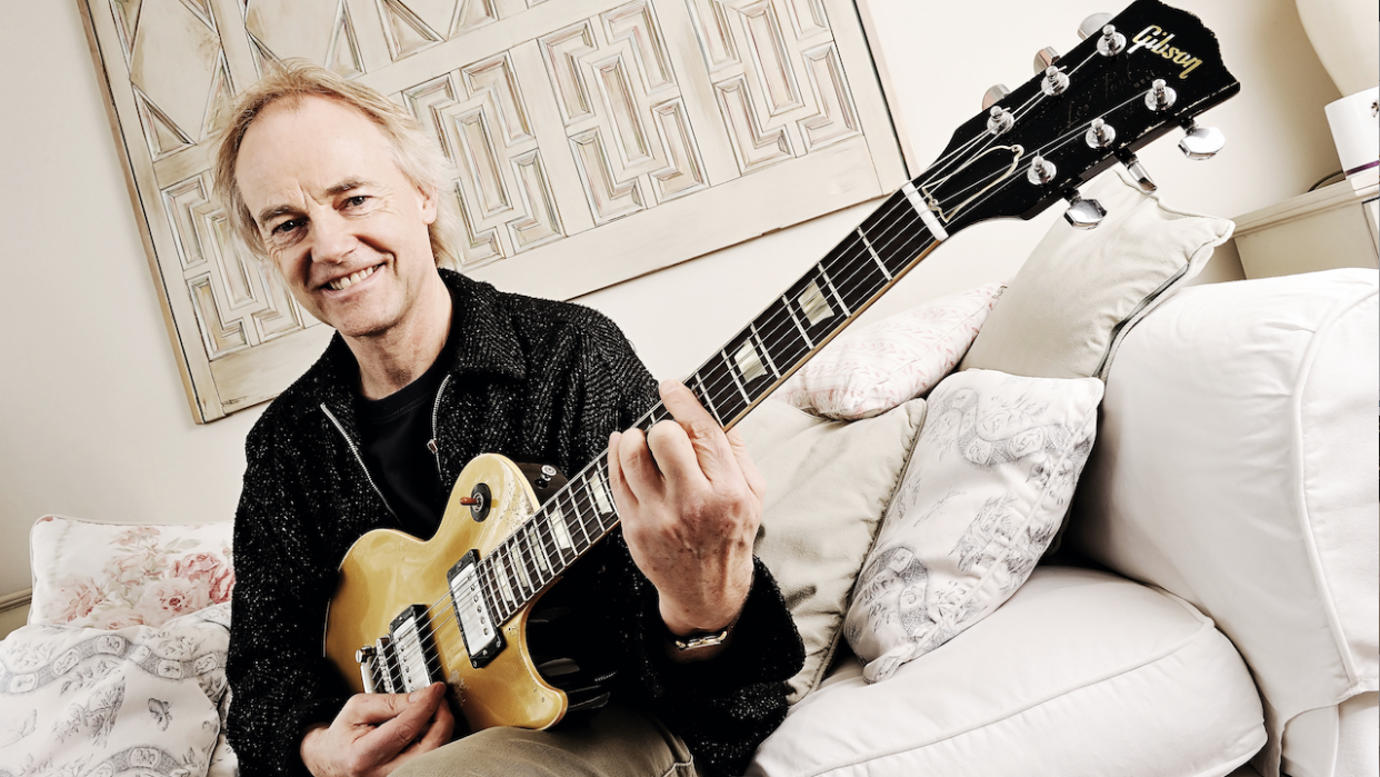  English guitarist Snowy White sits on a sofa playing his guitar. 