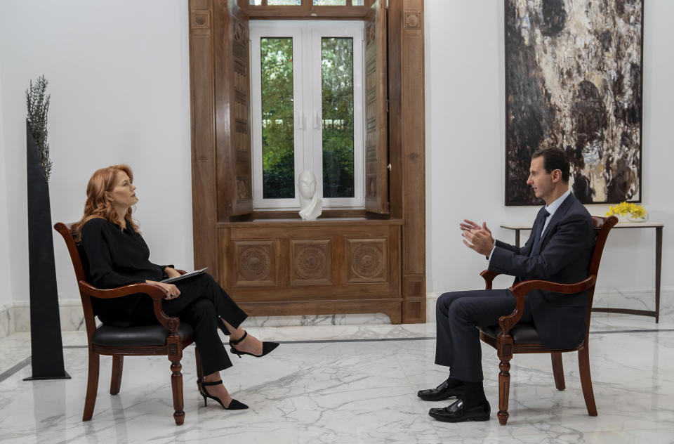 In this photo released on Monday Nov. 9, 2019 by the Syrian official news agency SANA, Syrian President Bashar Assad, right, speaks during an interview with Monica Maggioni, left, the CEO of Italy's Rai News 24, in Damascus, Syria. Assad said in an interview aired Monday that the global chemical weapons watchdog has faked and falsified a report over an attack near the capital Damascus last year "just because the Americans wanted them to do so." (SANA via AP)