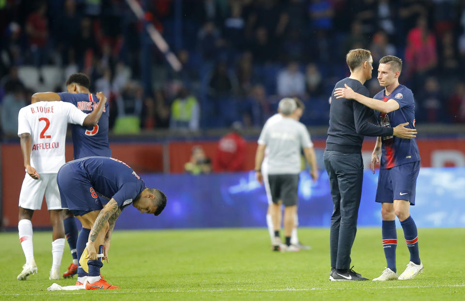 PSG's coach Thomas Tuchel, second right, embraces PSG's Julian Draxler after the French League One soccer match between Paris-Saint-Germain and Monaco at the Parc des Princes stadium in Paris, Sunday April 21, 2019. (AP Photo/Michel Euler)