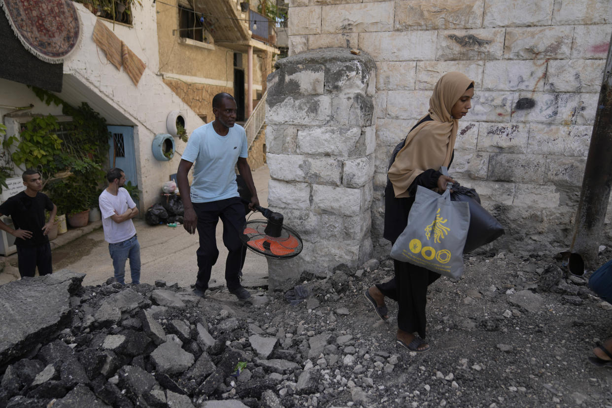 Palestinian refugees walk through a damaged road while they flee their homes during the Israeli army operation in the West Bank refugee camp of Tulkarem, in Tulkarem, Thursday, Sept. 5, 2024. (AP Photo/Nasser Nasser)