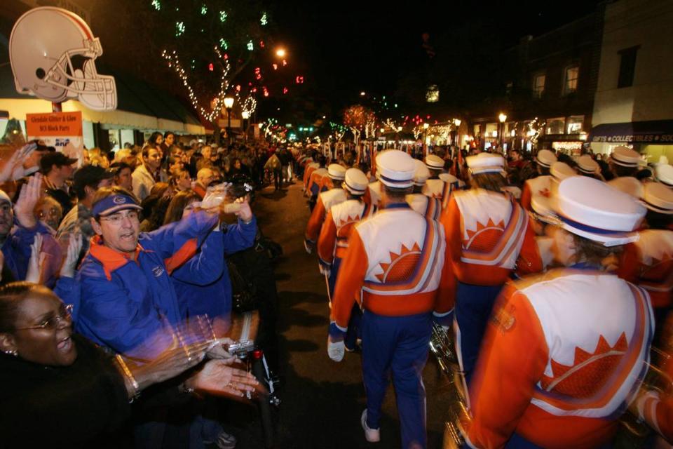 At another game, University of Florida fans do the Gator chomp as the Fightin’ Gator Marching Band marches past during a pre-game block party.