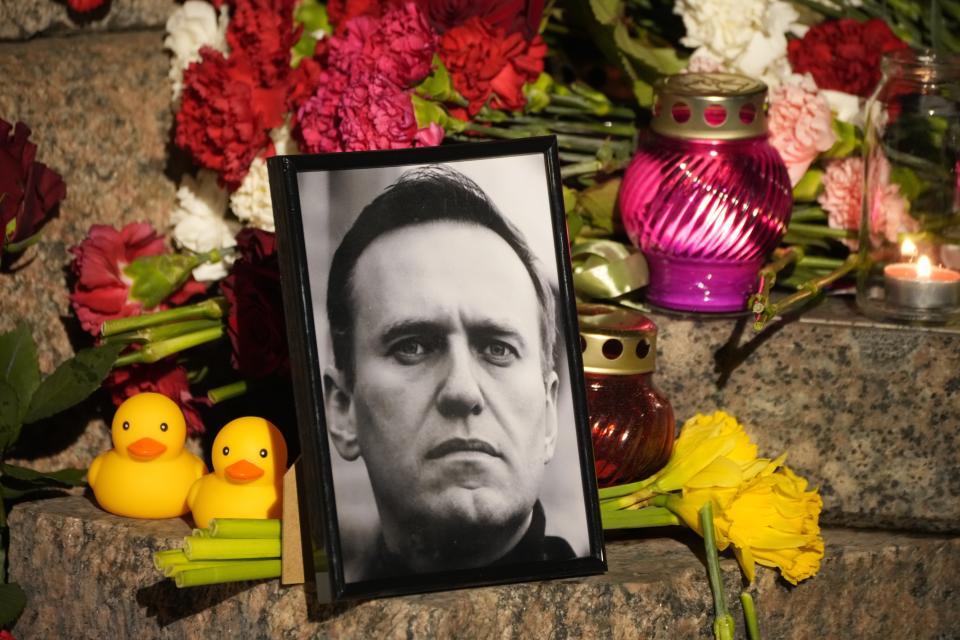 Un retrato del líder opositor ruso Alexei Navalny, flores y velas, durante un homenaje al activista en un monumento a las víctimas de la represión política, en San Petersburgo, Rusia, el 16 de febrero de 2024. (AP Foto/Dmitri Lovetsky)