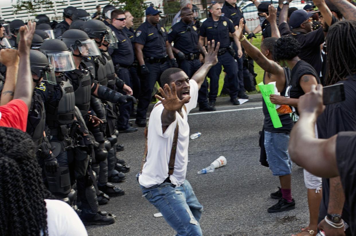 A man attempts to stop protesters from engaging with police in riot gear in front of the Baton Rouge Police Department headquarters after police attempted to clear the street in Baton Rouge, La., Saturday, July 9, 2016. Several protesters were arrested. (AP Photo/Max Becherer)