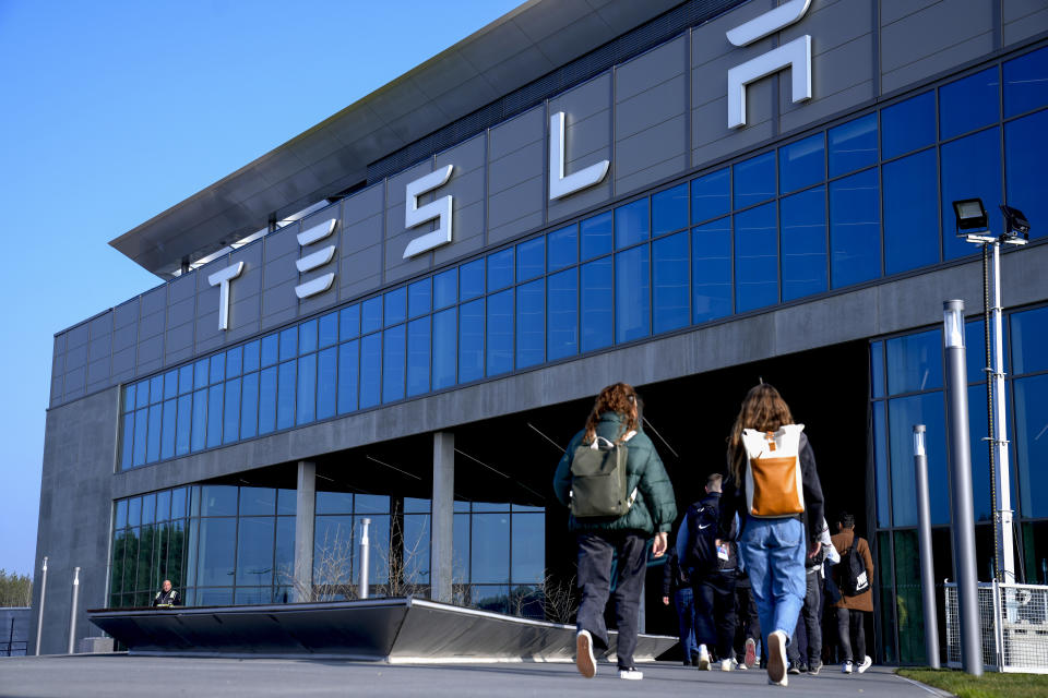 People walk to the Tesla Gigafactory for electric cars in Gruenheide near Berlin, Germany, Wednesday, March 13, 2024. Power has been restored to electric car manufacturer Tesla's factory near Berlin about a week after an outage believed to have been caused by arson, a network operator says. (AP Photo/Ebrahim Noroozi)
