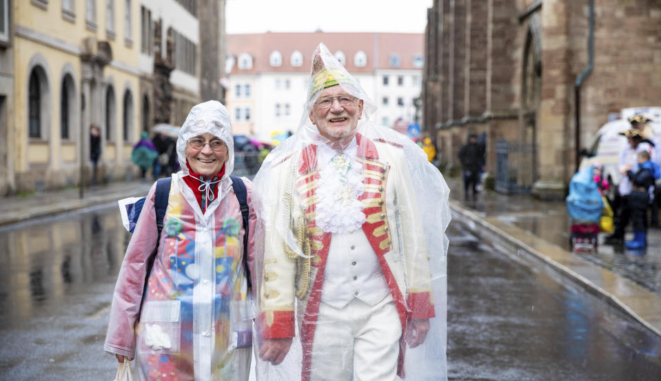 Two people wait in the rain for the beginning of the carnival parade 'Schoduvel' in Brunswick, northern Germany, Sunday, Feb. 23, 2020. Moritz Frankenberg/dpa via AP)