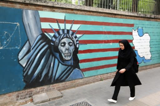 An Iranian woman walks past a mural on the wall of the former US embassy in the Iranian capital Tehran on May 8, 2018