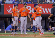 Houston Astros' Mauricio Dubón, left, José Abreu, center, wait as Victor Caratini, right, crosses home plate after Caratini's three-run home run during the fifth inning of a baseball game against the Texas Rangers, Monday, April 8, 2024, in Arlington, Texas. (AP Photo/Gareth Patterson)