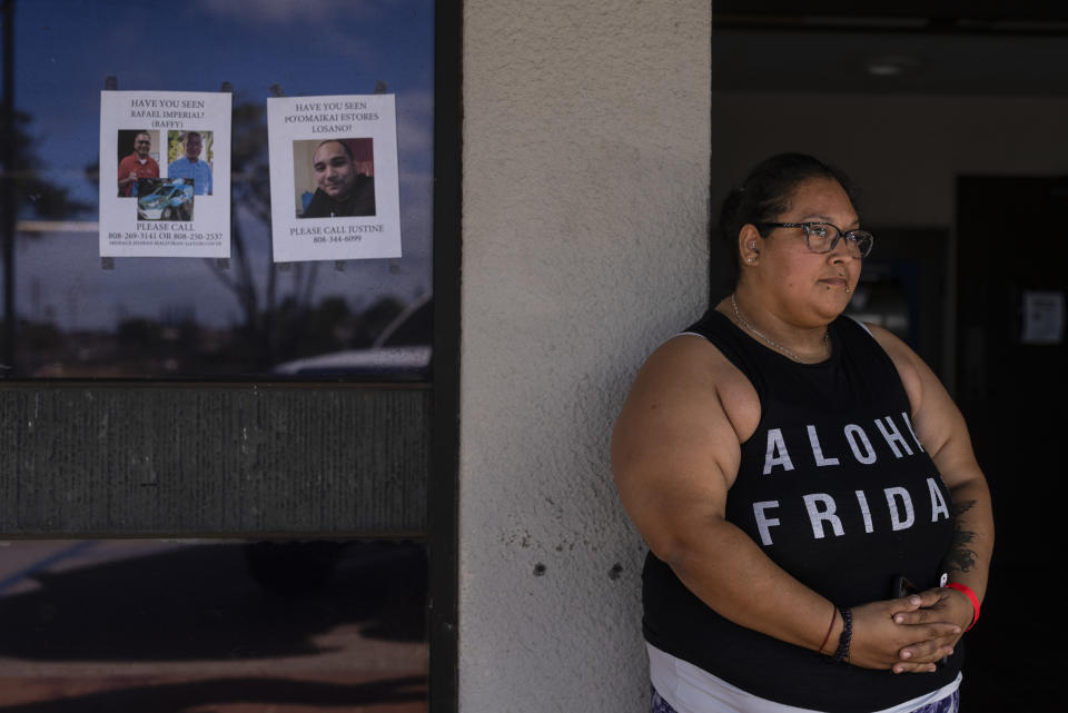 Guadalupe Gonzalez, a Lahaina, Hawaii, resident who survived a deadly wildfire, stands next to missing person flyers while waiting for a post office to open in Lahaina, Hawaii, Monday, Aug. 21, 2023. Gonzalez said she and her family had to drive through the fire twice while fleeing the town. (AP Photo/Jae C. Hong)
