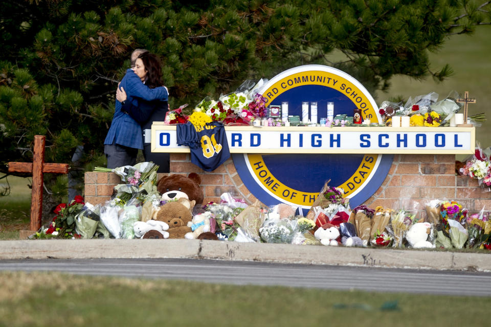 FILE - Michigan Gov. Gretchen Whitmer embraces Oakland County Executive Dave Coulter as the two leave flowers and pay their respects on Dec. 2, 2021 at Oxford High School in Oxford, Mich. Since the start of 2020, researchers at the Naval Postgraduate School have recorded 504 cases of gun violence at schools — a number that eclipses the previous eight years combined. (Jake May/The Flint Journal via AP, File)